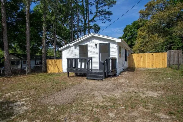 a view of a house with a yard and large tree