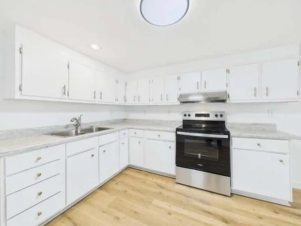 a kitchen with granite countertop white cabinets and stainless steel appliances