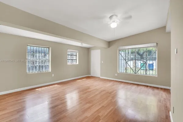 a view of an empty room with a window and wooden floor