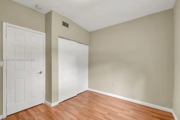 a view of an empty room with wooden floor and closet area