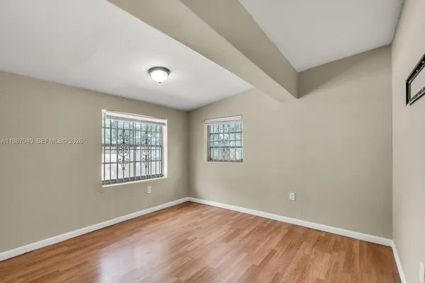 an empty room with wooden floor and windows