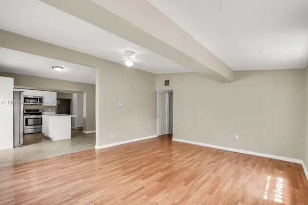a view of an empty room with wooden floor and a window