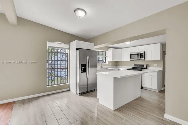 a kitchen with stainless steel appliances granite countertop a refrigerator oven a sink dishwasher and white cabinets with wooden floor