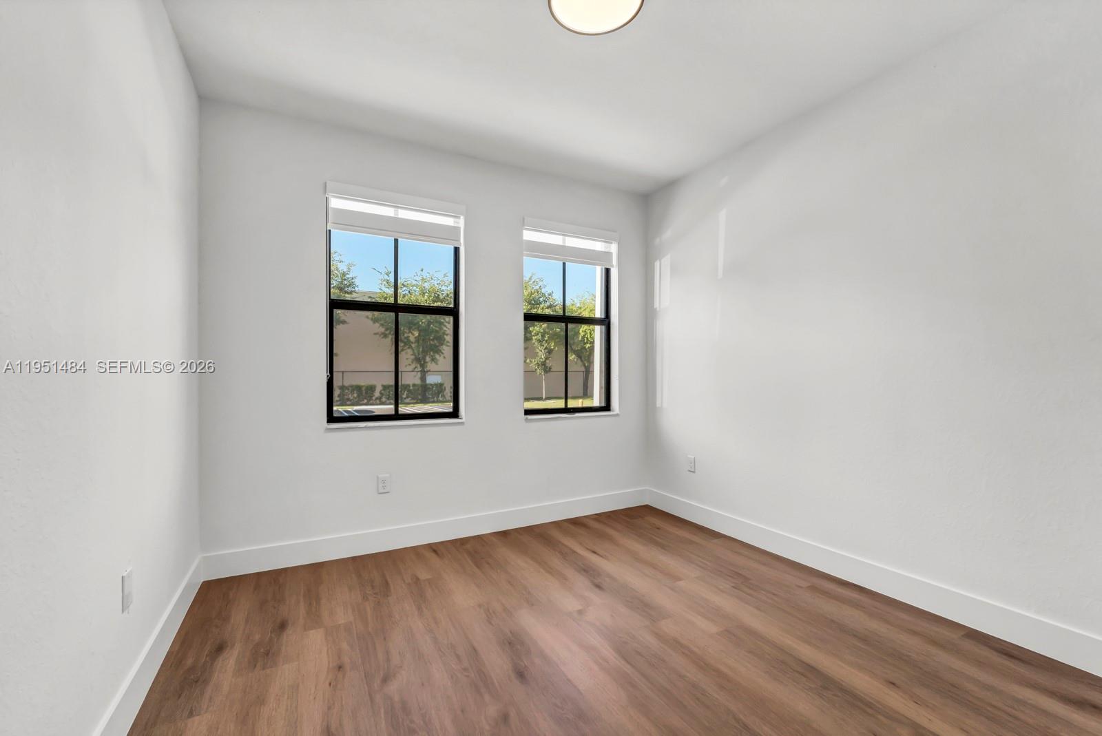 13067 Southwest 286th Street, Unit 13067 Homestead, FL 33033 - Photo 19 of 37 an empty room with wooden floor and windows