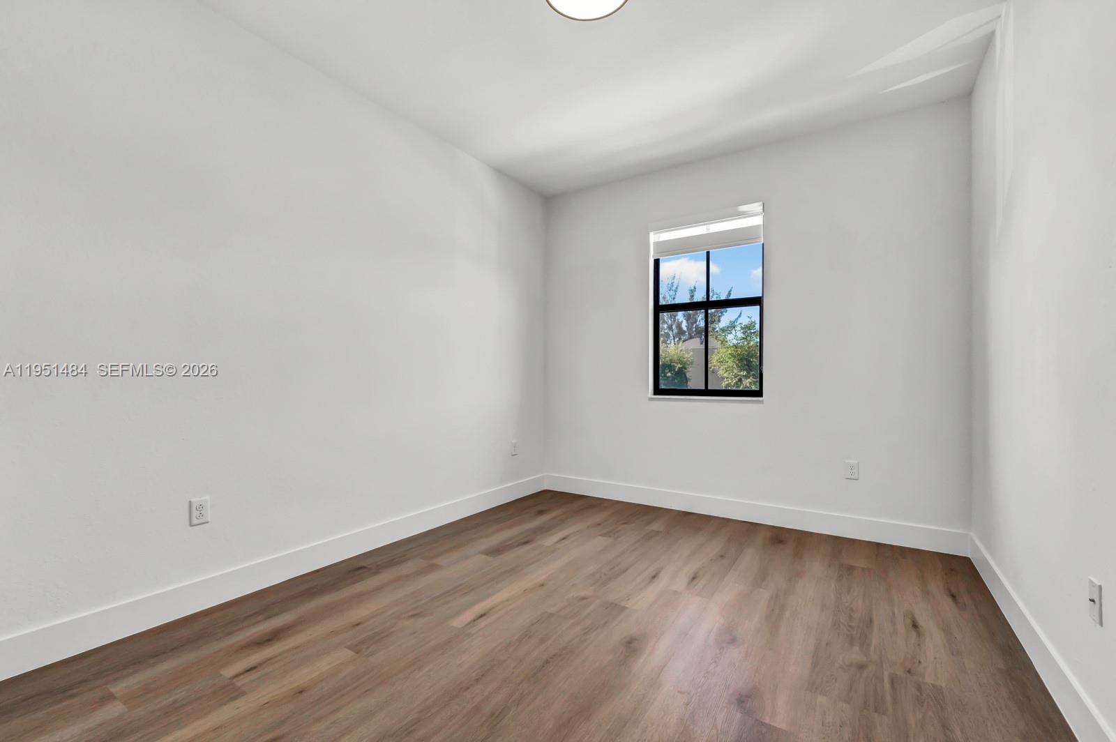 13067 Southwest 286th Street, Unit 13067 Homestead, FL 33033 - Photo 23 of 37 an empty room with wooden floor and windows