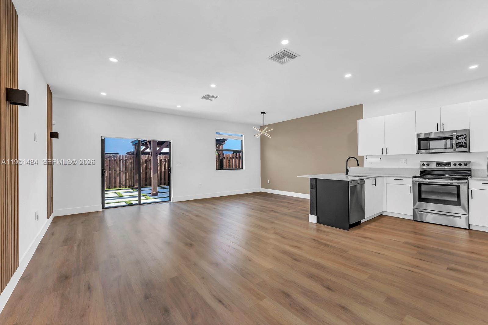 13067 Southwest 286th Street, Unit 13067 Homestead, FL 33033 - Photo 3 of 37 a view of kitchen with stainless steel appliances granite countertop a stove top oven a sink dishwasher and a oven with wooden floors