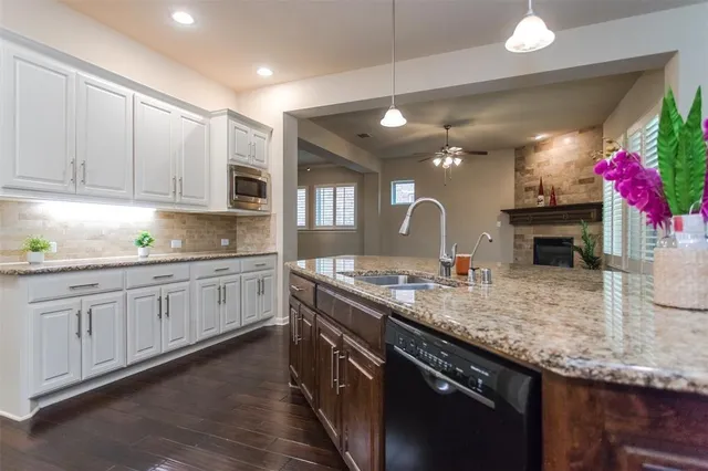 a kitchen with granite countertop a sink and white cabinets