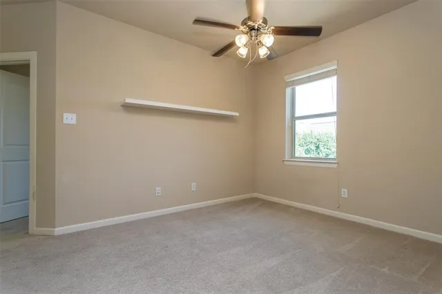 an empty room with a window and a fan