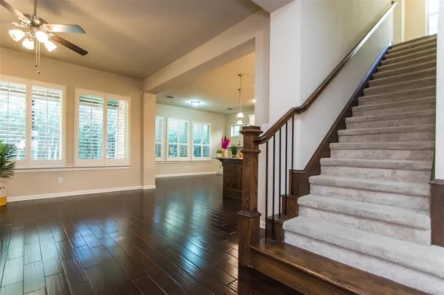 a view of staircase with wooden floor and fan