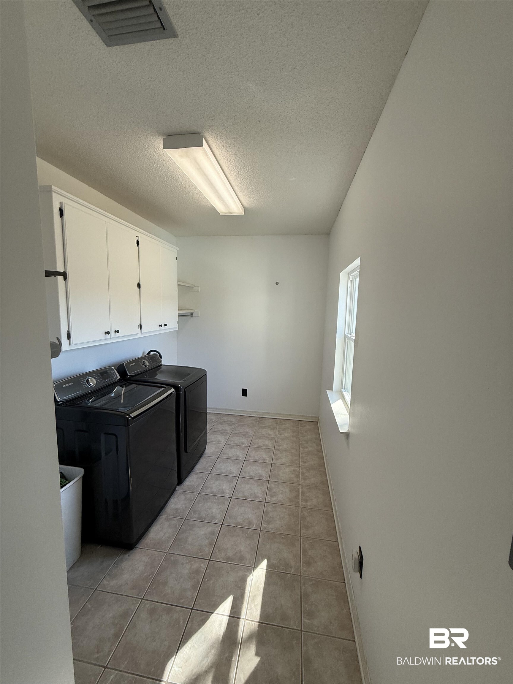 100 Orleans Way Daphne, AL 36526 - Photo 12 of 31 Washroom with cabinet space, light tile patterned floors, visible vents, washing machine and clothes dryer, and a textured ceiling
