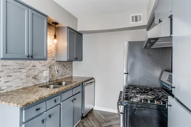 a kitchen with granite countertop a sink stove and cabinets