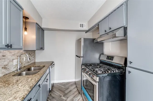 a kitchen with granite countertop a sink stove and refrigerator