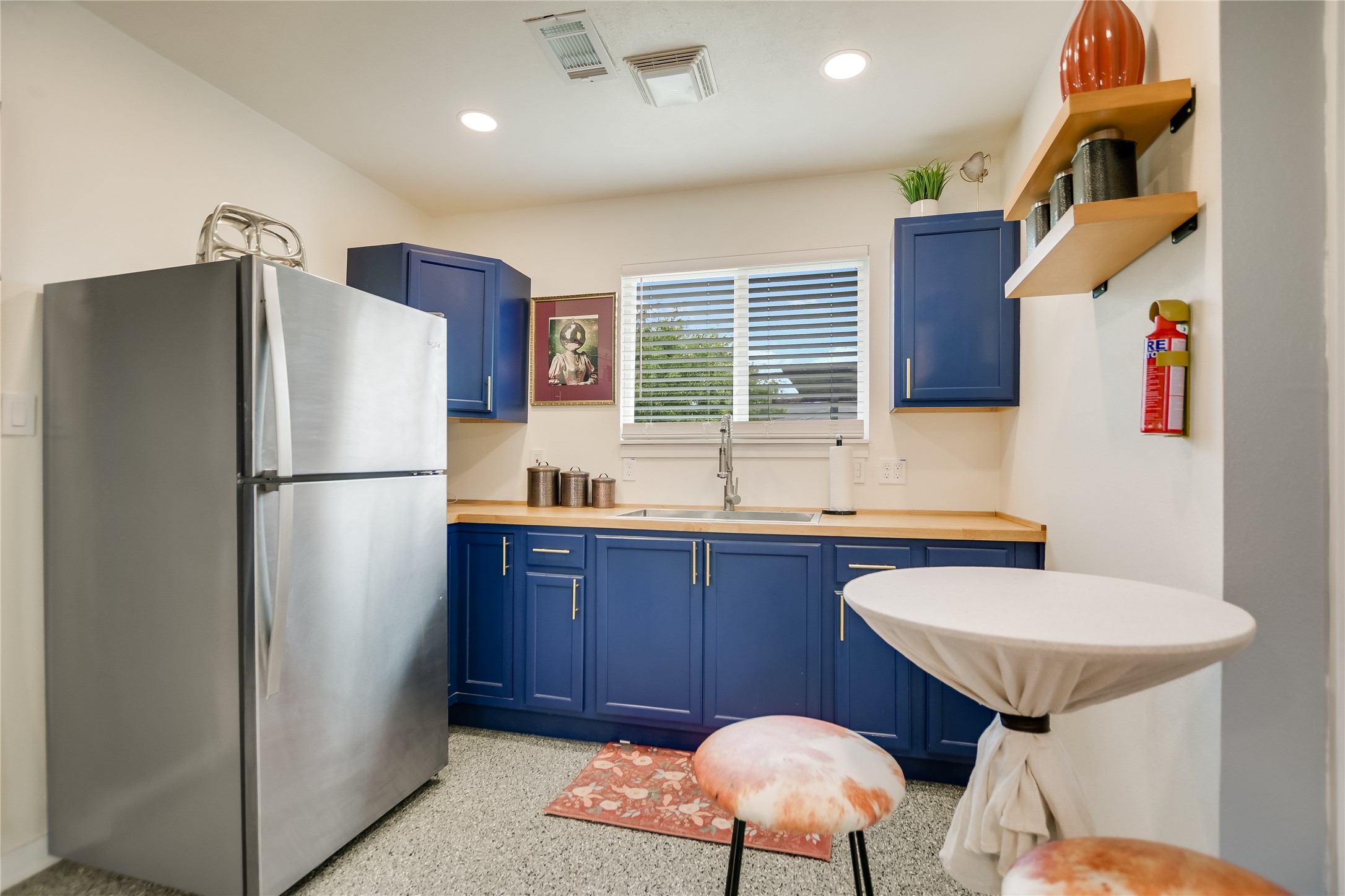 4702 Crest Oak Road Austin, TX 78744 - Photo 19 of 20 Compact kitchen featuring deep blue cabinetry, wood-finish countertops, and a stainless steel refrigerator