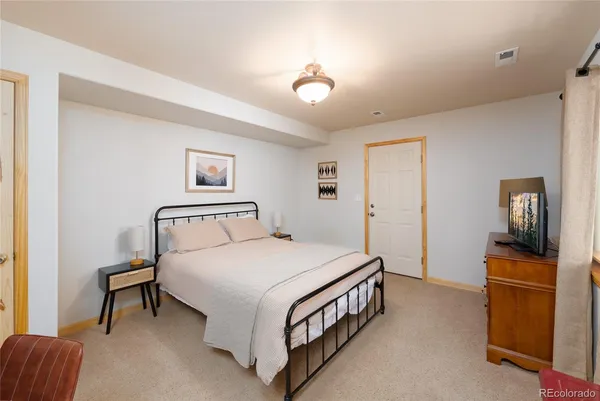 a bedroom with a bed and a flat tv screen on dresser