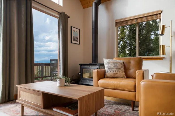 a living room with furniture a floor to ceiling window and kitchen view
