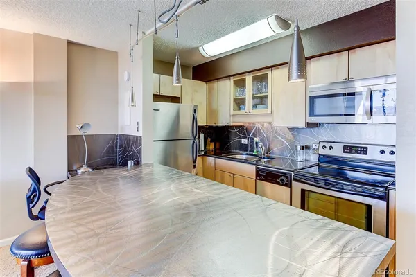 a kitchen with stainless steel appliances kitchen island granite countertop a table chairs in it and wooden floors