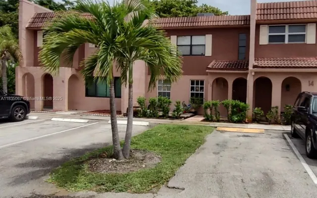 a front view of a house with yard and parking
