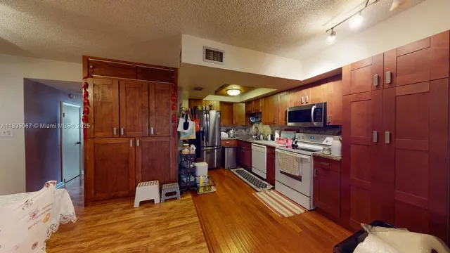 a kitchen with stainless steel appliances kitchen island granite countertop a refrigerator stove and cabinets