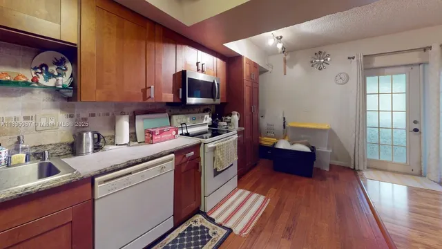 a kitchen with stainless steel appliances granite countertop a stove a sink dishwasher and a microwave oven with wooden floor