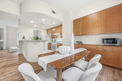 a kitchen with stainless steel appliances kitchen island granite countertop a dining table chairs and sink