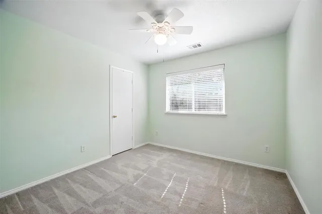 an empty room with windows and fan
