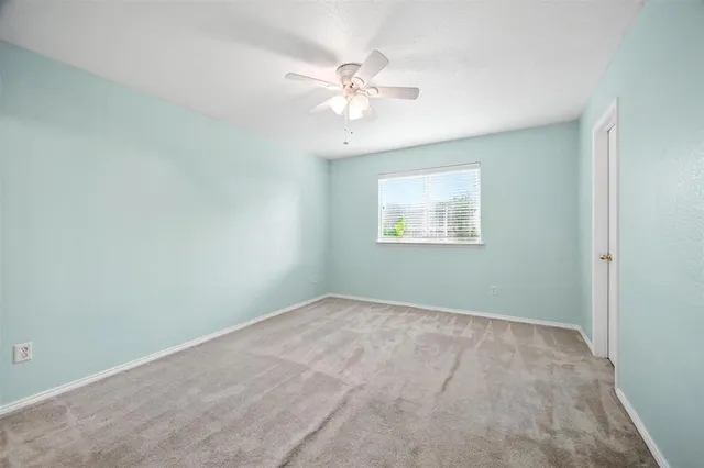 an empty room with a window and a fan