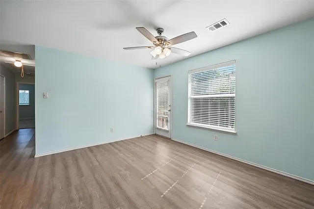 a view of an empty room with a window and wooden floor