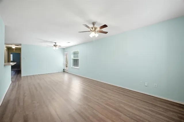 a view of a room with wooden floor and a ceiling fan