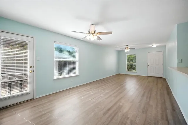a view of an empty room with a window and wooden floor