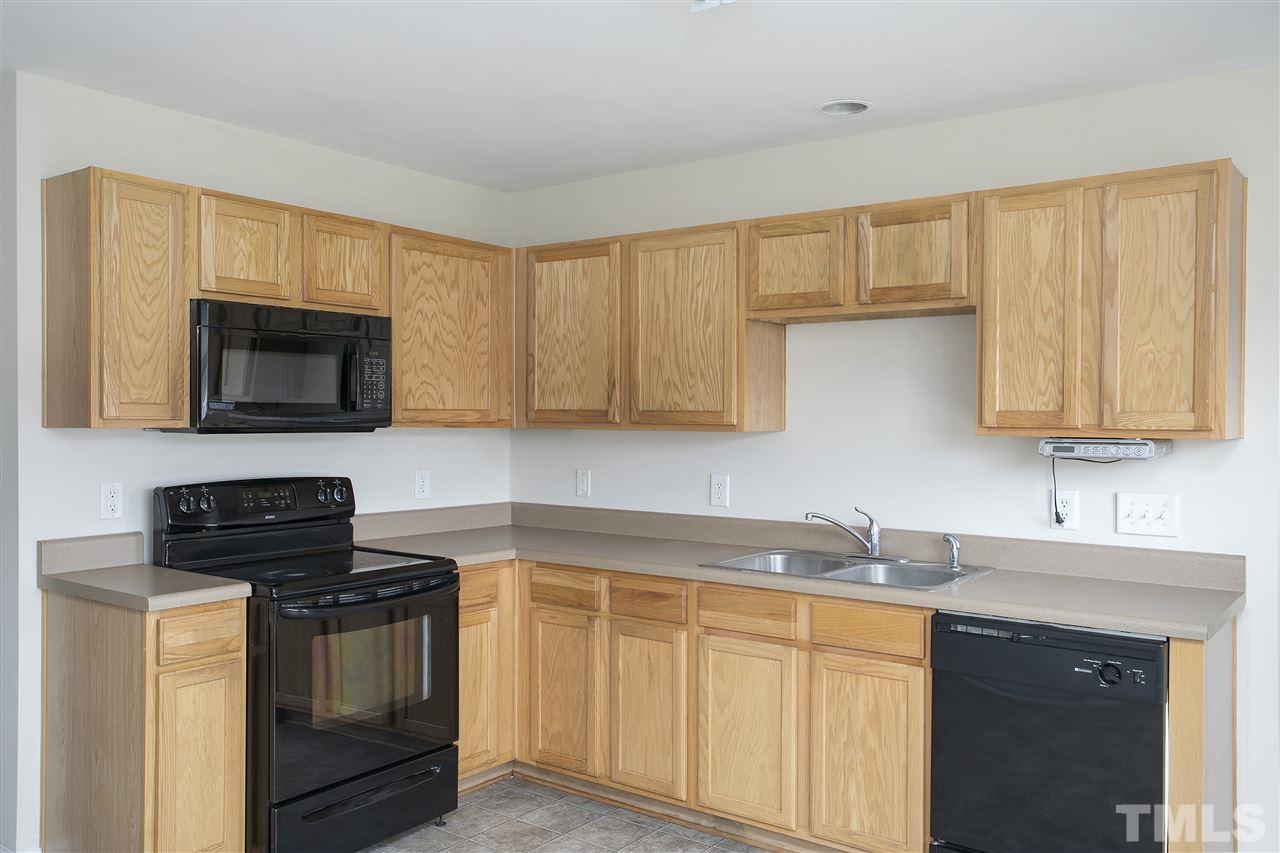 1112 Lombar Street Raleigh, NC 27610 - Photo 7 of 19 a kitchen with granite countertop white cabinets and black appliances