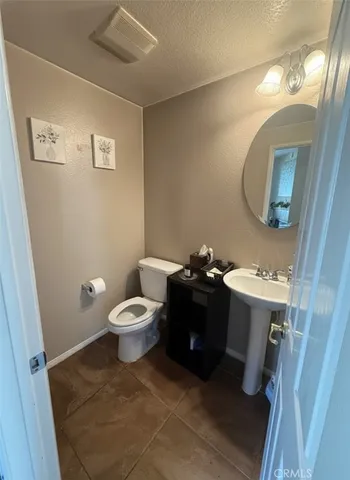 a bathroom with a toilet sink vanity granite and mirror