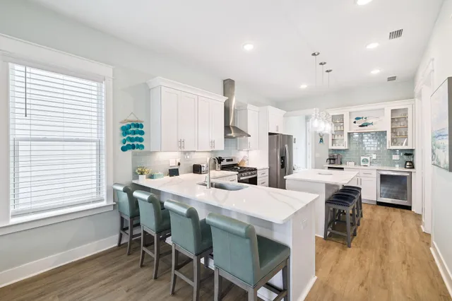 a kitchen with stainless steel appliances a refrigerator a stove a sink a dining table and chairs