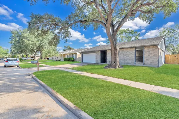 a view of a house with a big yard and large tree
