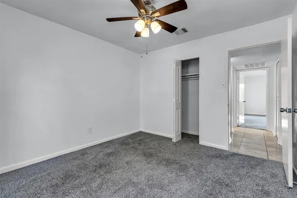 an empty room with closet and a chandelier fan