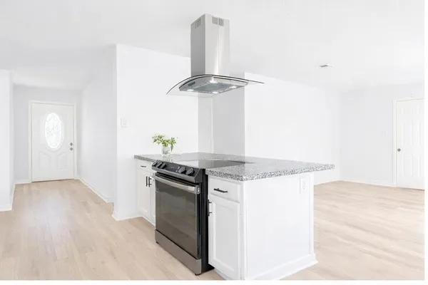 a kitchen with a stove and a wooden floor