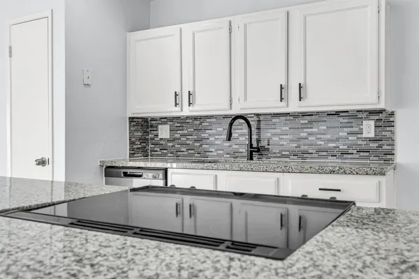 a kitchen with stainless steel appliances granite countertop a sink a stove and white cabinets