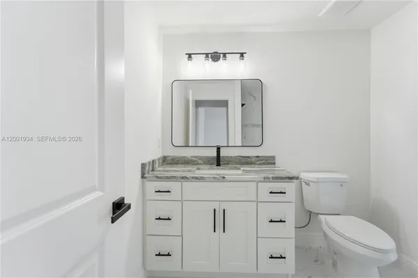 a bathroom with a granite countertop toilet sink and mirror