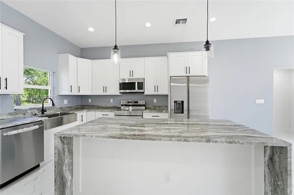 a kitchen with kitchen island sink stove and white cabinets