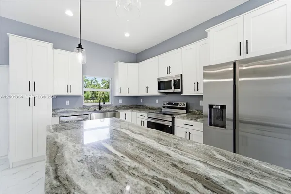 a kitchen with granite countertop a refrigerator stove and microwave