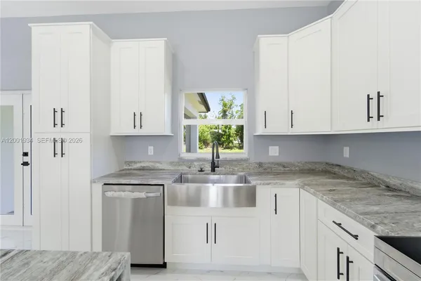 a kitchen with stainless steel appliances granite countertop a sink a stove and a white refrigerator