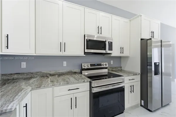a kitchen with granite countertop white cabinets and stainless steel appliances