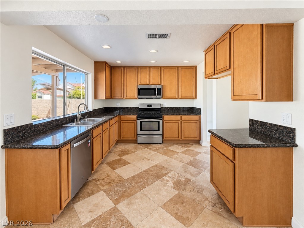 43 Bayridge Road Henderson, NV 89074 - Photo 24 of 47 Gleaming stone countertops and classic wood cabinetry surround a patterned tile floor in this kitchen.