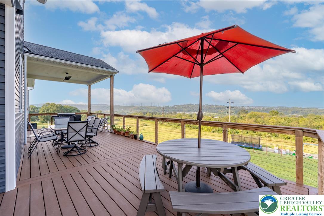4733 Egypt Road Coplay, PA 18037 - Photo 3 of 40 a view of a balcony with table and chairs under an umbrella with wooden floor