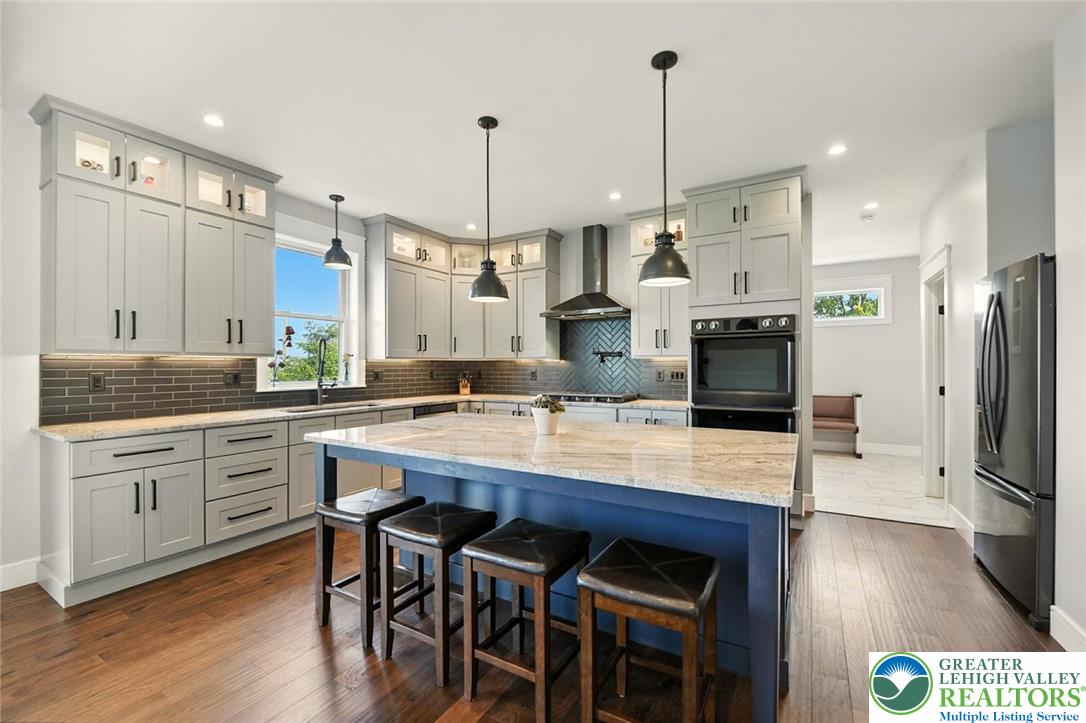 4733 Egypt Road Coplay, PA 18037 - Photo 4 of 40 a kitchen with stainless steel appliances kitchen island granite countertop a stove a sink a center island a refrigerator and a wooden floor