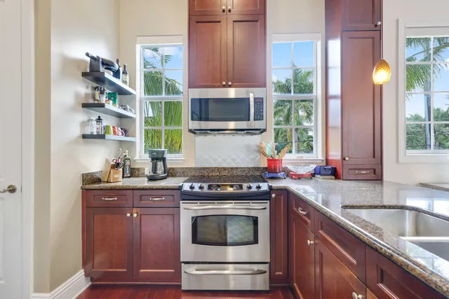 a kitchen with stainless steel appliances granite countertop a stove a sink and a microwave
