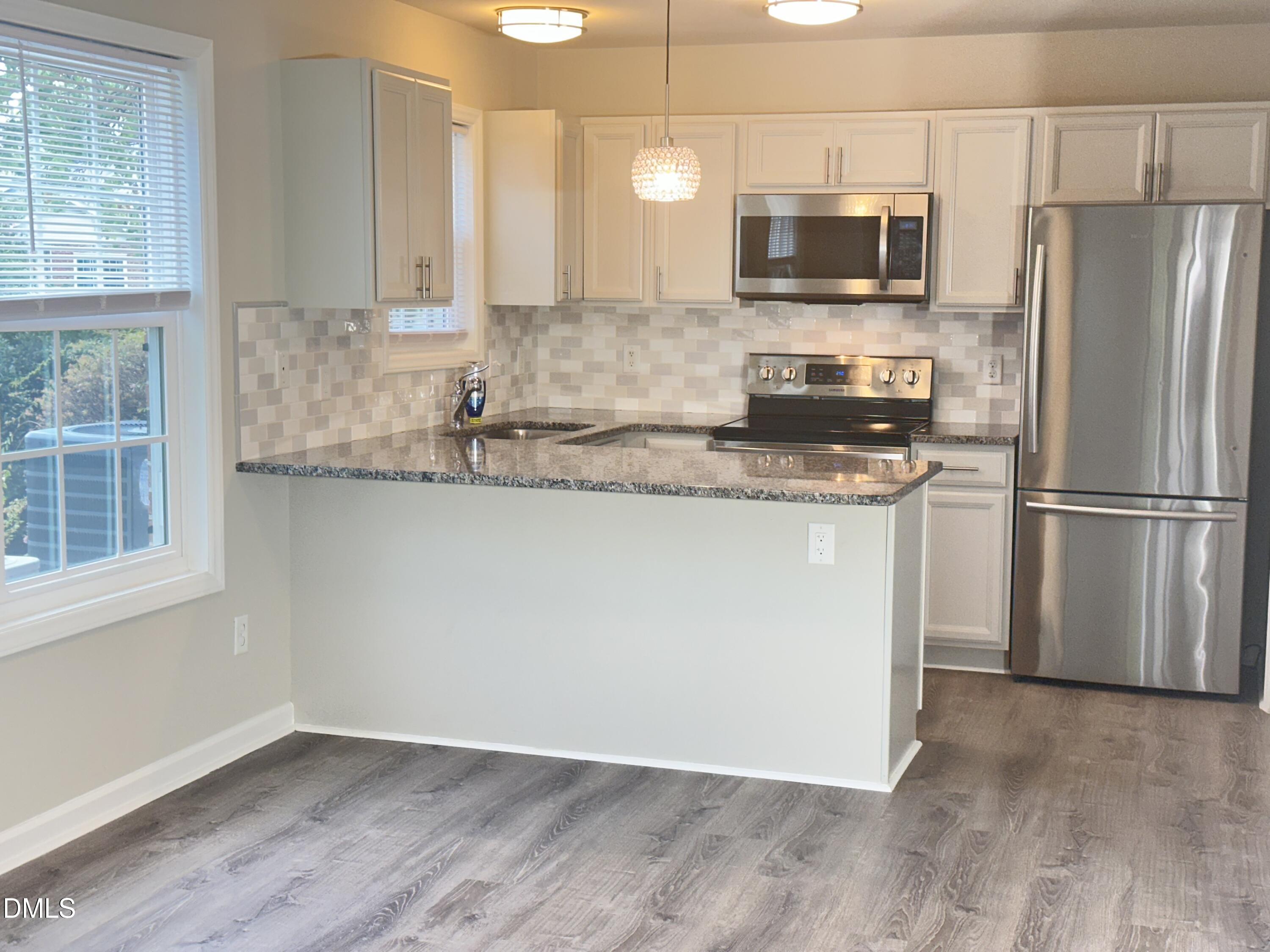 2813 Wellington Ridge Loop Cary, NC 27518 - Photo 6 of 46 Kitchen featuring granite countertops, stainless steel appliances, Tile backsplash, and updated cabinetry.