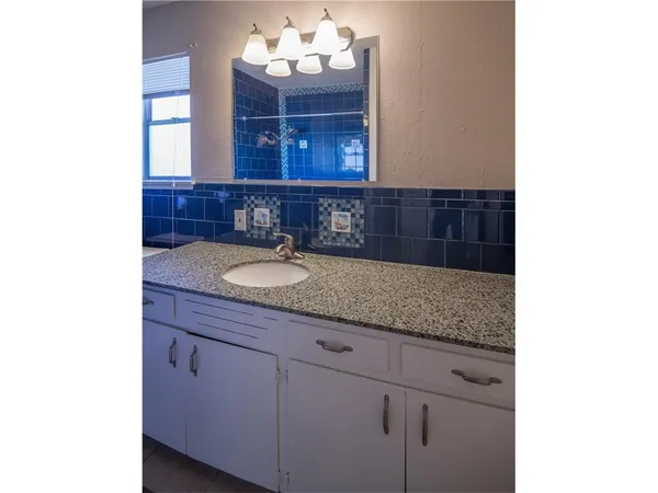 a bathroom with a granite countertop sink and a mirror