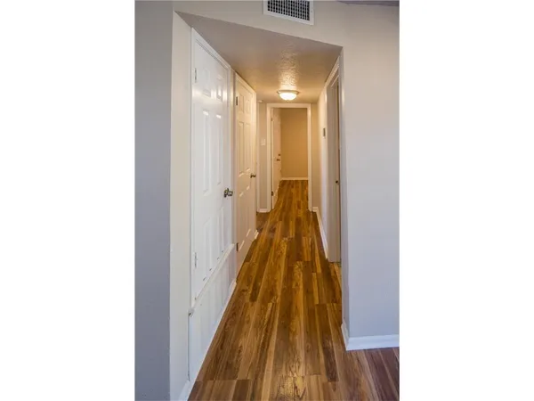 a view of an empty room with wooden floor and a ceiling fan