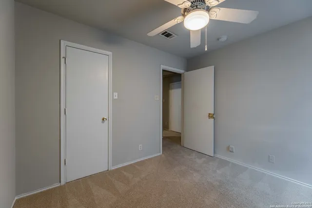 a view of an empty room with a chandelier fan