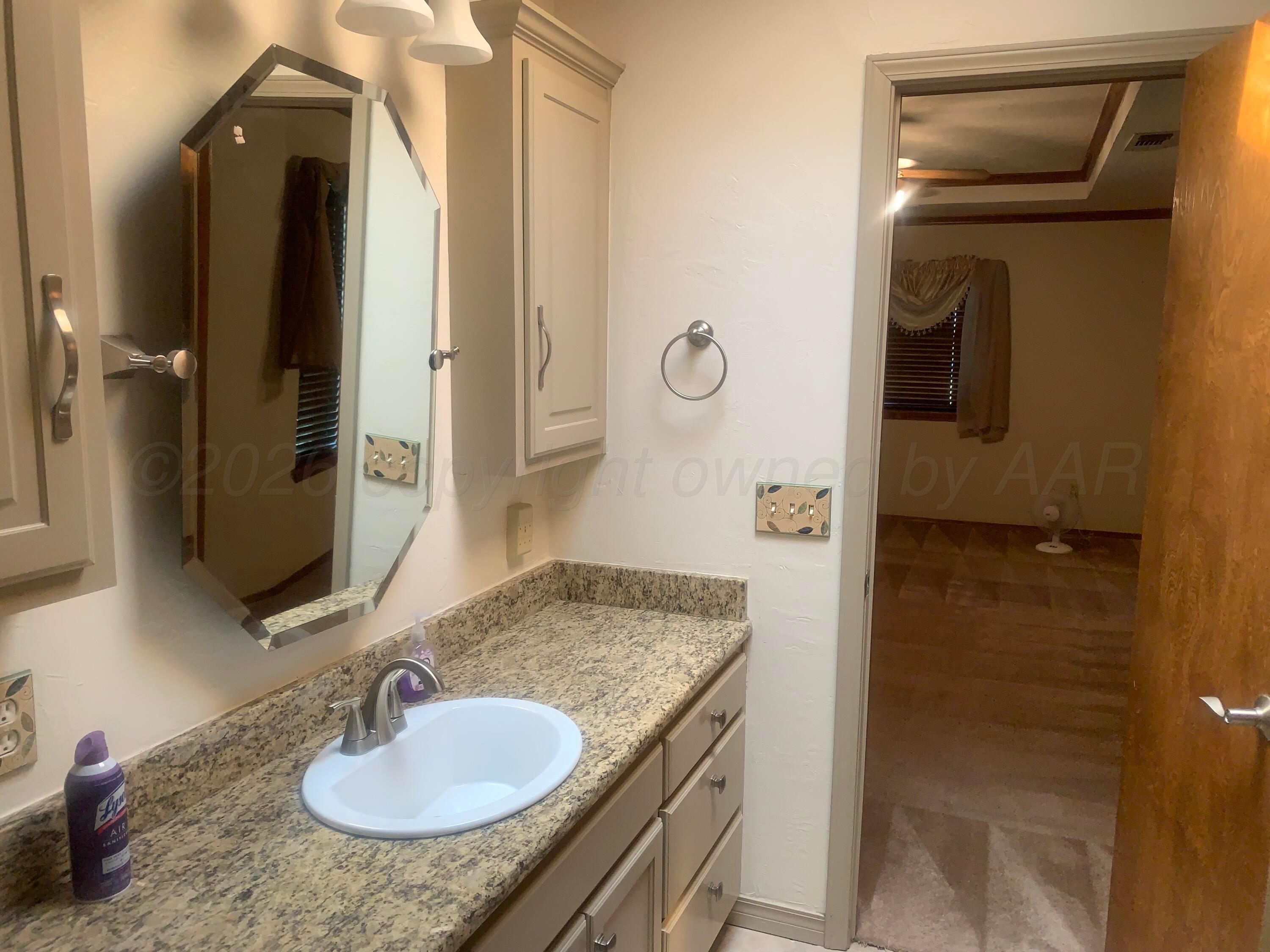 6101 Ridgewood Drive Amarillo, TX 79109 - Photo 16 of 28 a bathroom with a granite countertop sink and a mirror